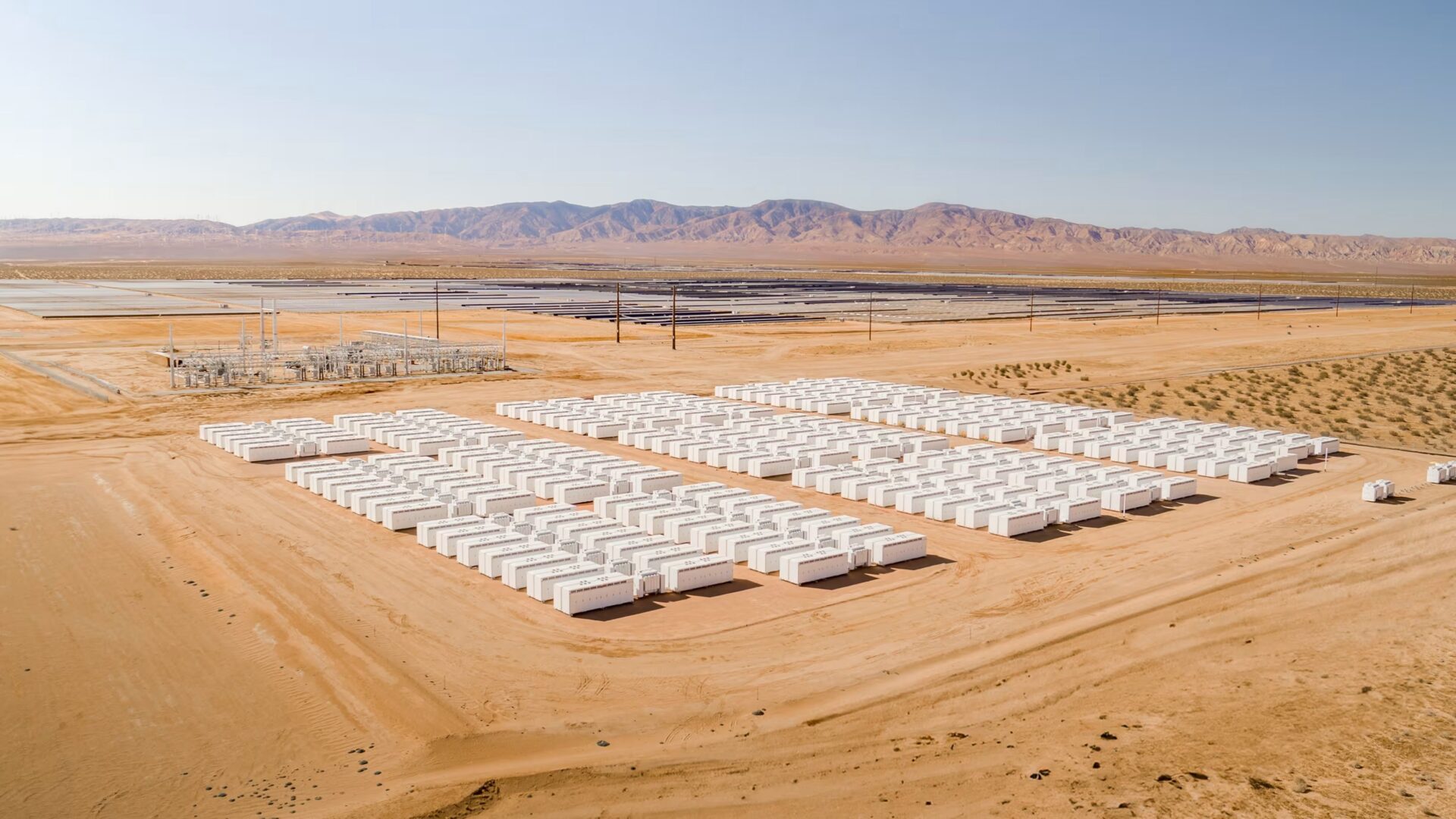 Rows of Tesla Megapack battery units at a large desert energy storage site