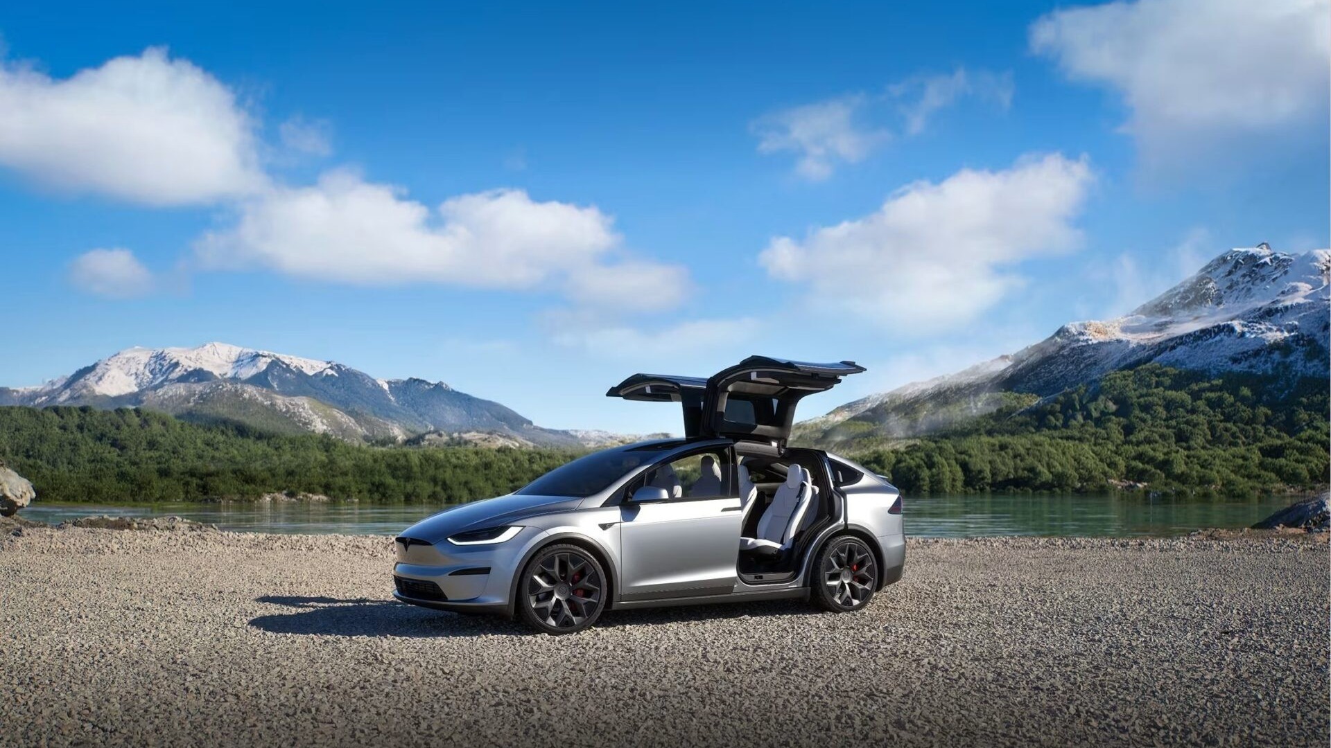 Silver Tesla Model X with Falcon Wing doors open beside a mountain lake