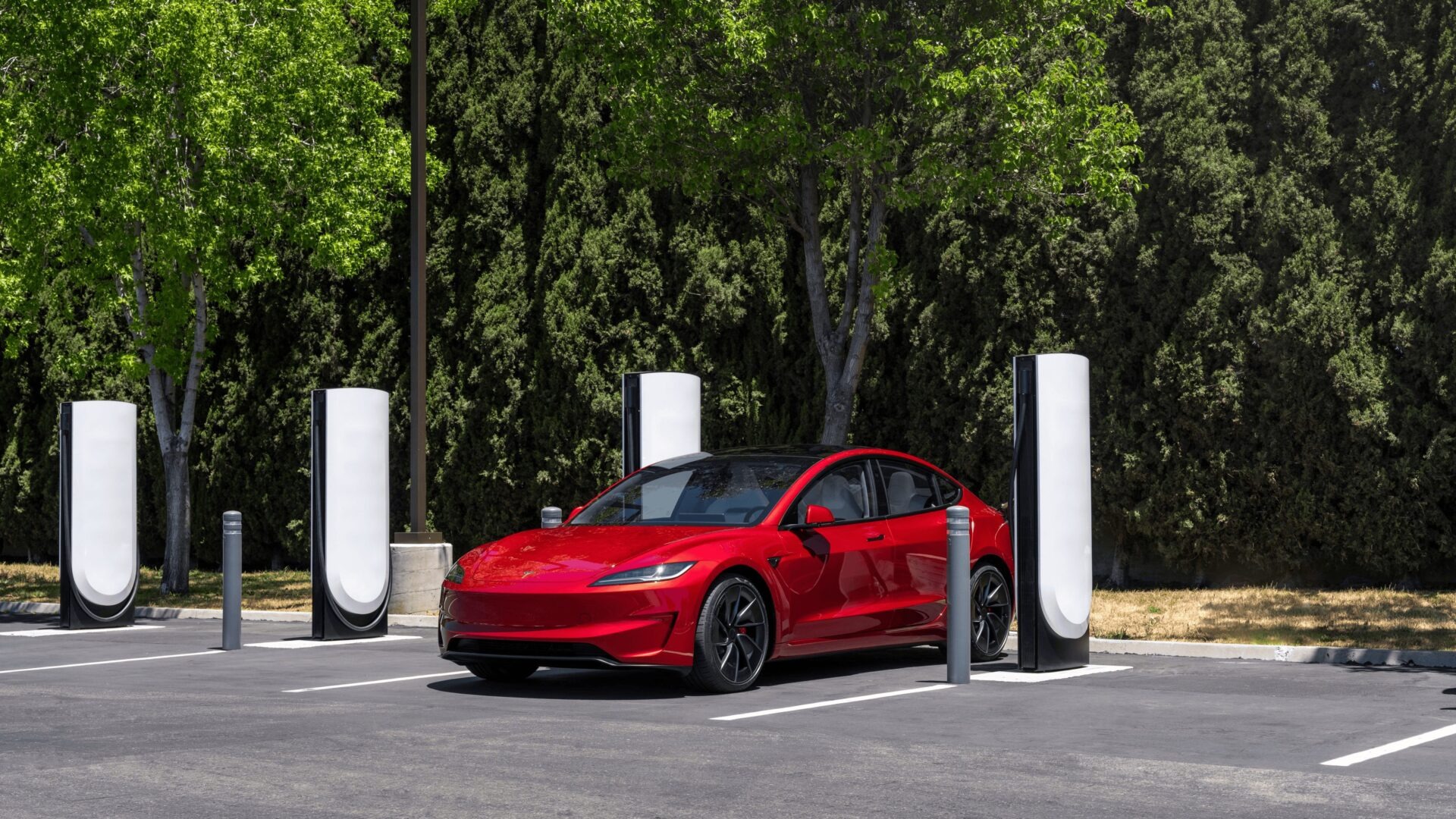 Red Tesla Model 3 plugged into a white V4 Supercharger