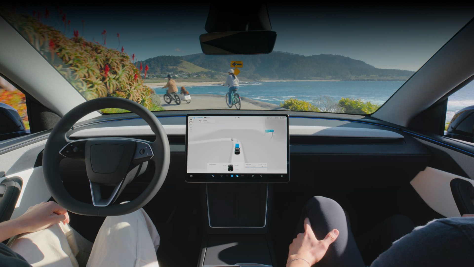 Interior view of a Tesla driving along a coastal road with FSD Supervised engaged